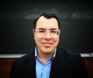 Dan Moller headshoot in front of a blackboard