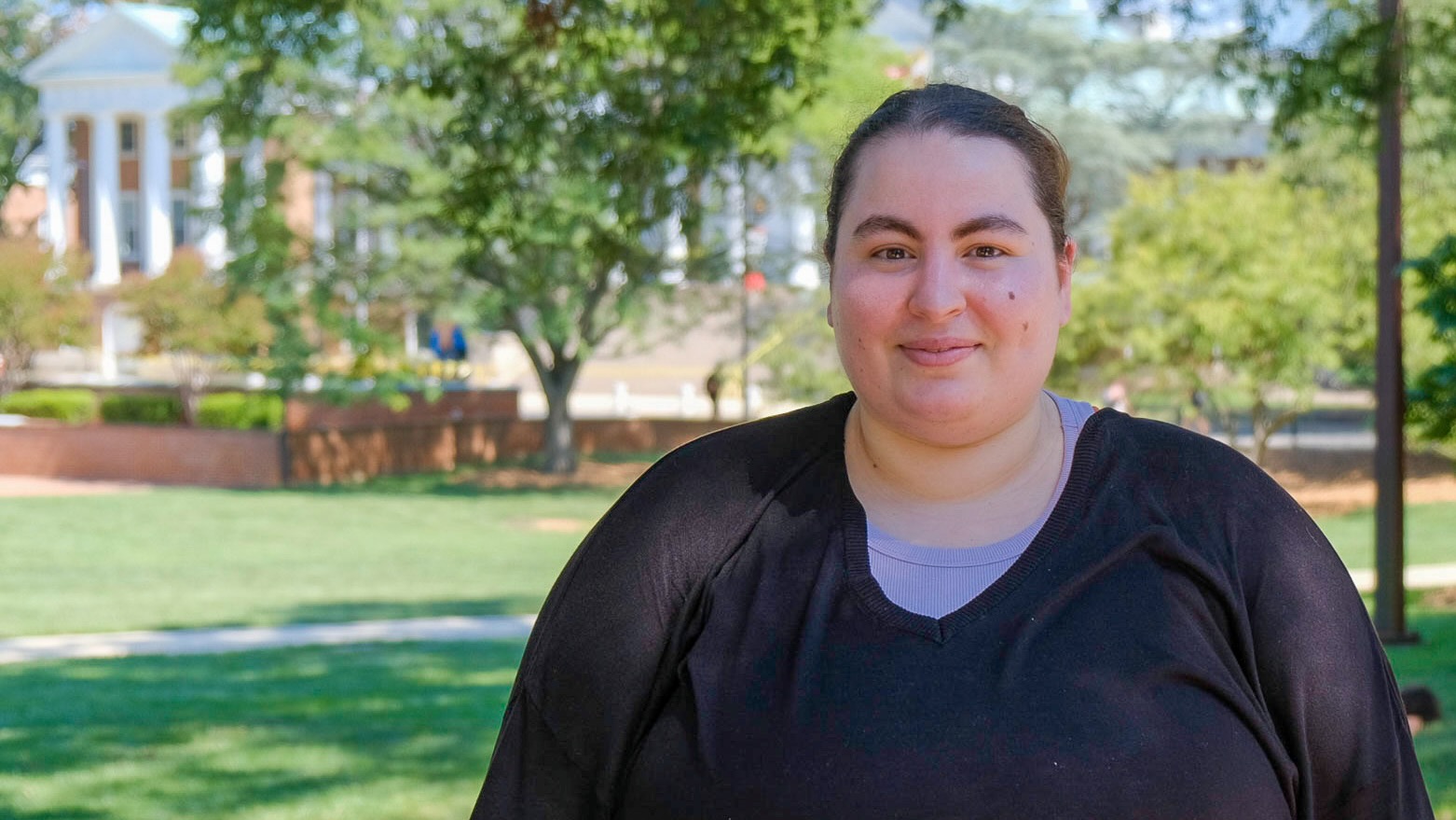 Sarah Boukendour, PhD student in linguistics, standing outside on McKeldin Mall in the sunshine.