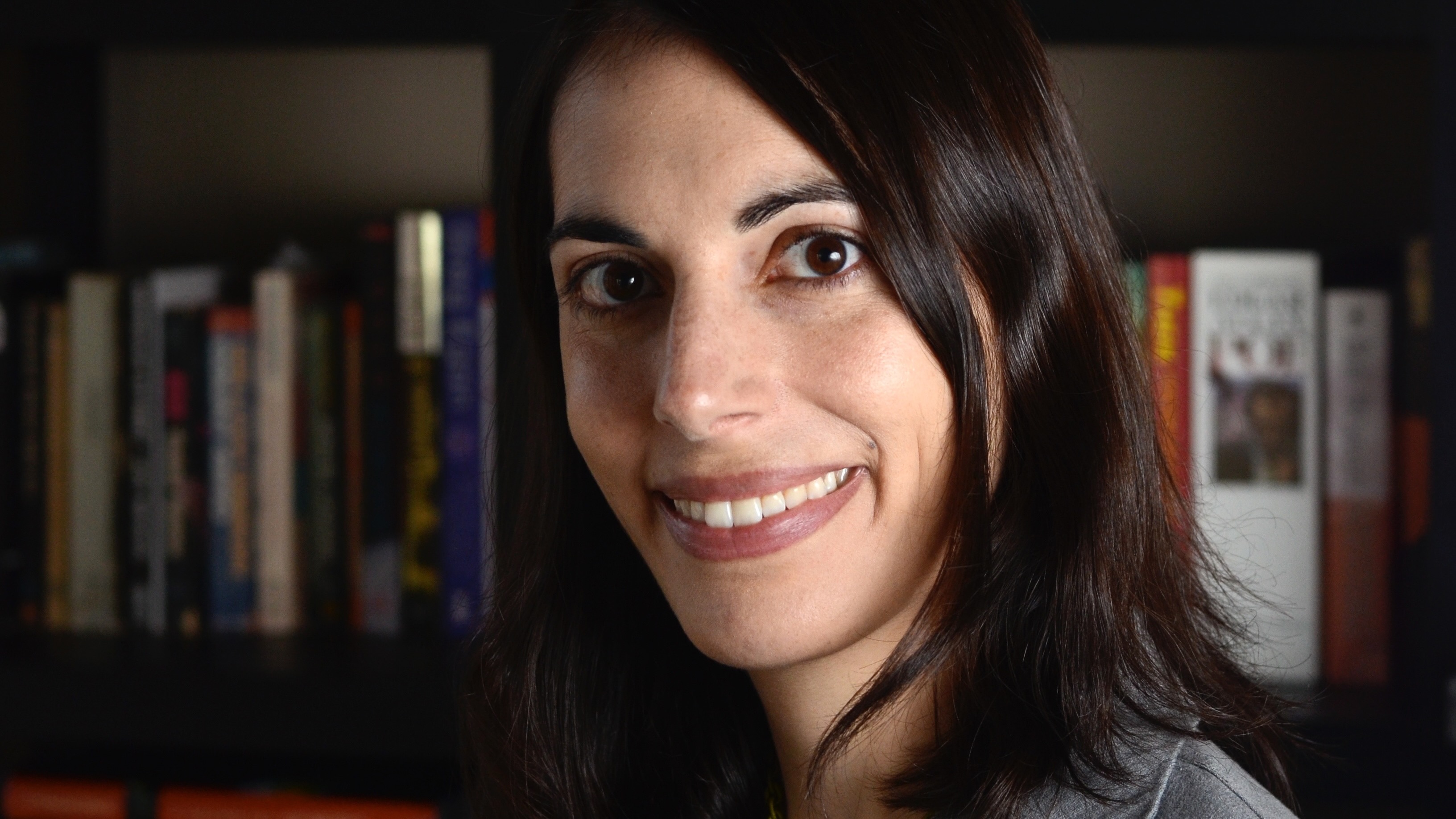 Close portrait of a woman with dark brown hair in a dark room.