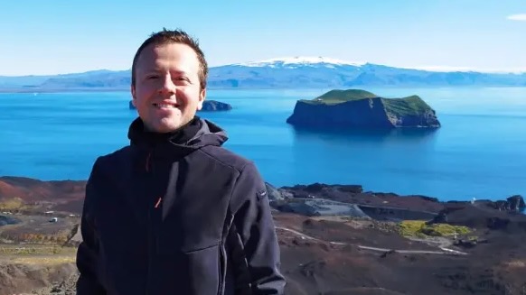 A young man standing at a fjord in arctic Iceland.
