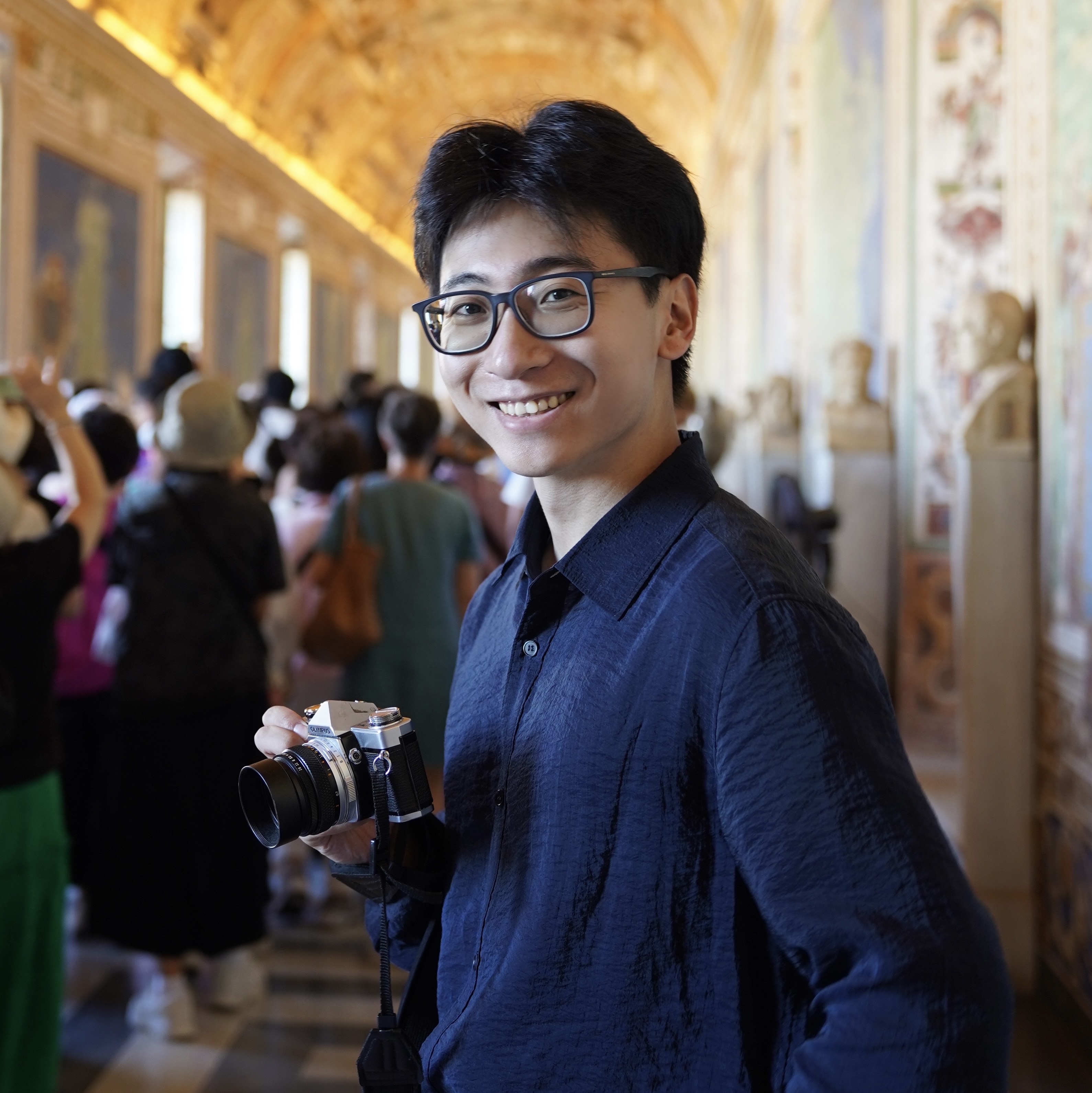 A young man in an old hallway, holding a camera.