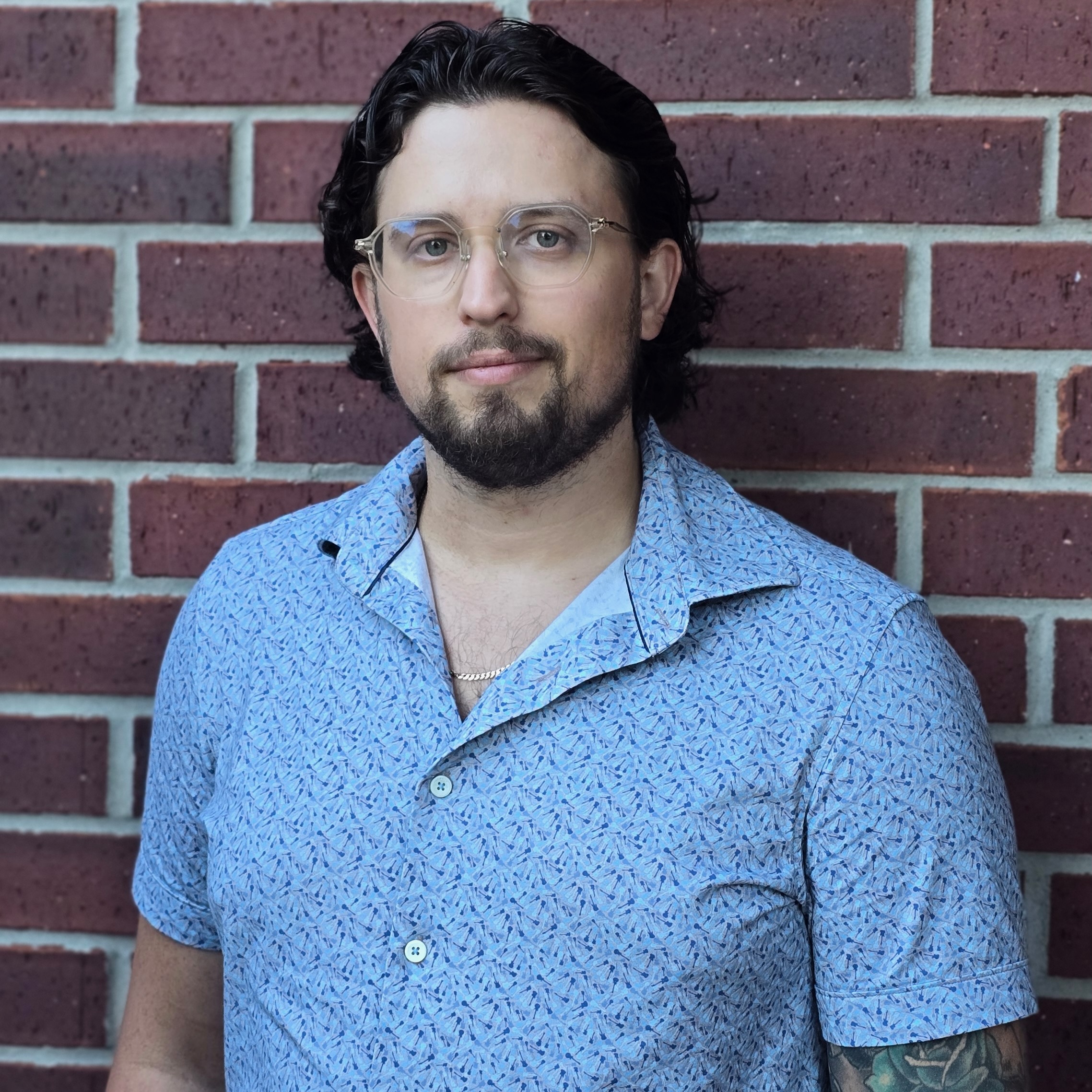 Portrait of young man, standing in front of a brick wall.