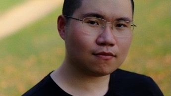 Close portrait of a young man, standing outside.