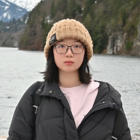 A young woman standing in front of an alpine lake.